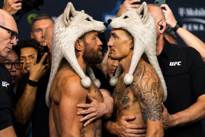 Two shirtless MMA fighters, one wearing a wolf hat and embracing face-to-face during a UFC weigh-in stare-down, with the "UFC" logo visible on a staff member's shirt in the background.

The image ties to the post's $WOLF meme theme, with the fighters' wolf hats and aggressive face-off mirroring the "bringing the trenches back to life" spirit, while the "nobody saw it coming" line plays on the surprise spectacle of a UFC weigh-in moment.