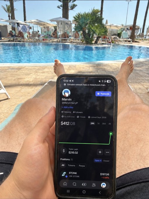 A man relaxes by a pool, holding a phone showing the Robinhood app with a portfolio value of $412.08 for user 'Marvin' (@MarvinHarryP).