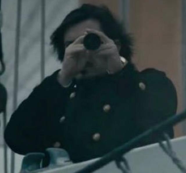 A man in a dark military-style coat peers through a spyglass, suggesting he's watching from afar—mirroring the post's message that major trading platforms are quietly observing before revealing their Robinhood Chain integrations.