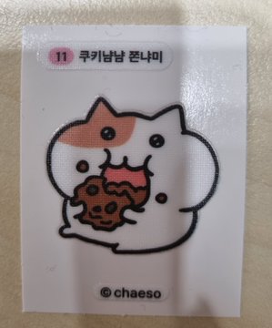 A cute cartoon cat sticker by chaeso (label 11, 쿠키남달 폰케이) eating a chocolate cookie with pink frosting.