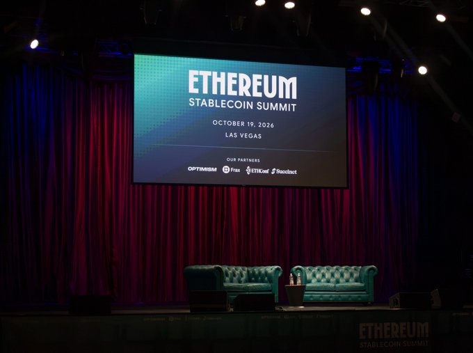 An empty conference stage set up for the 'ETHEREUM STABLECOIN SUMMIT' on October 19, 2026 in Las Vegas, with sponsor logos for Optimism, Frax, EthHub, and Soundnet displayed on the screen.