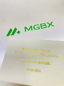 A greeting card or promotional material featuring the 'MGBX' logo in green, with Chinese text wishing prosperity and success, signed 'MGBX团队' (MGBX Team).