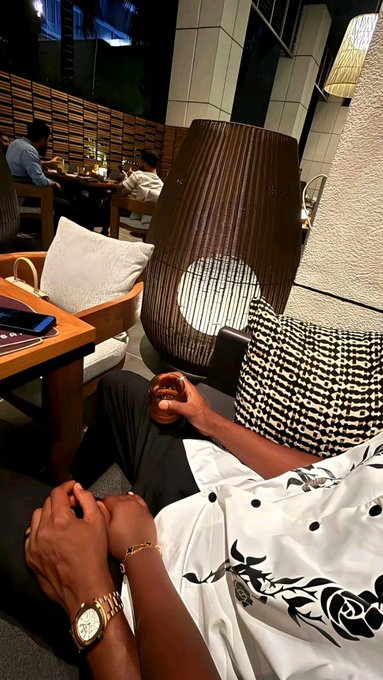 A person lounges on a cushioned chair in a dimly lit lounge or hotel setting, wearing a white patterned shirt and a watch, with their hands resting on their lap. The relaxed, nighttime vibe of the scene pairs well with the post's "goodnight" message and hopeful anticipation for green candles for $RIVER.
