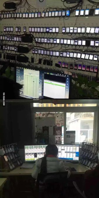 A person sits at a desk monitoring multiple computer screens displaying security camera feeds, with an extensive wall of smartphones above them showing various screens, including several showing emergency call interfaces.