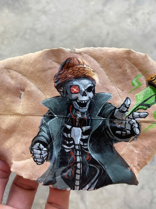 A detailed artwork painted on a dried leaf depicting a cyborg/robotic skeleton character wearing sunglasses and a coat, holding what appears to be a weapon with green energy.