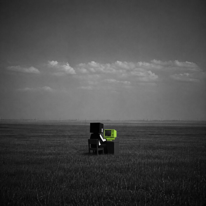 A black and white photograph showing a small dark figure sitting at a desk with an old computer in a vast, empty field under a cloudy sky.