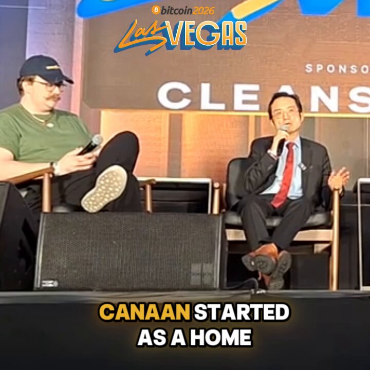 In this image, there are two men sitting next to each other with microphones in front of them. One man has a microphone while the other one does not. They appear to be at an event or gathering where they are speaking into their respective microphones. The background features a banner that says "Las Vegas" and "Canaan started as a home". This suggests that the event is related to cryptocurrency, specifically the mining process of Canaan, which has been described as being done from the comfort of one's own home.