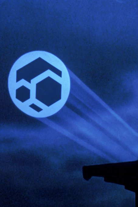 A blue Komodo logo (a geometric lizard/honeycomb design inside a circle) is projected against a dark blue night sky.
