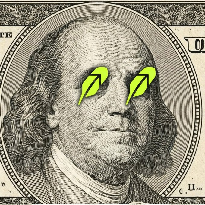 A close-up of Benjamin Franklin's face on a U.S. hundred-dollar bill has been edited with bright neon-green Robinhood feather logos placed over his eyes. The image cleverly links Robinhood's brand identity with Franklin, reinforcing the post's claim that "The future of money runs through Robinhood."