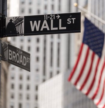 The image shows the iconic Wall Street and Broad Street signs in New York's financial district, with an American flag waving nearby. These street signs visually anchor the post's announcement about a landmark moment for U.S. financial infrastructure—on-chain Treasury settlements executed on Wall Street institutions' traditional turf.