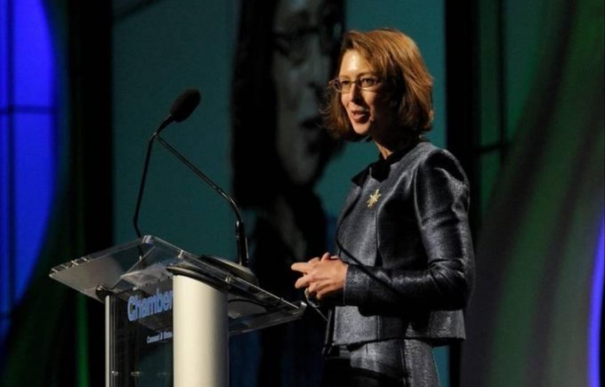A woman with red hair and glasses speaks at a podium labeled "Greenberg" against a dark backdrop. The image illustrates the growing institutional embrace of Bitcoin, as the CEO's comment signals Wall Street's shifting stance toward including cryptocurrency in long-term wealth strategies.