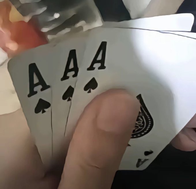 A hand holds four aces of spades in a card game.