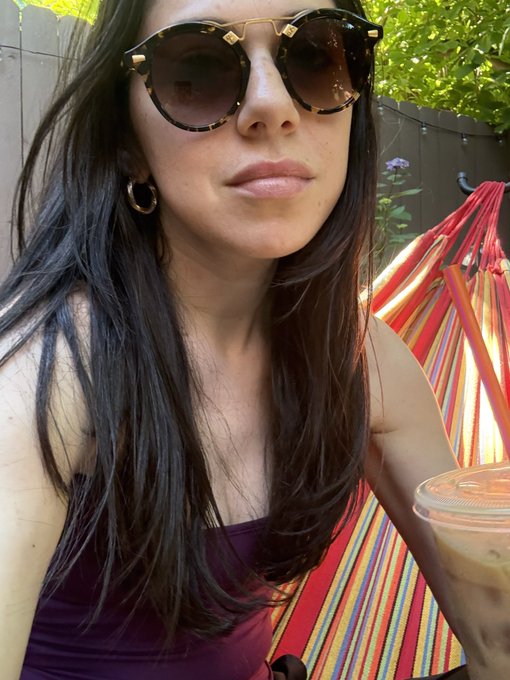 The image features a woman wearing sunglasses, with long hair that falls over her shoulders. She is sitting outdoors under a striped umbrella or hammock, holding a drink in one hand while wearing sunglasses. The background includes trees, suggesting an outdoor setting like a park or garden. The caption of the image reads "gm it's a beautiful last day of spring", which implies that the woman is enjoying the pleasant weather and the blossoming season.

The post seems to be promoting a relaxing atmosphere during the warmer months, as evidenced by the woman's attire and the outdoor setting. It could also be an advertisement for sunglasses or other summer-related products.