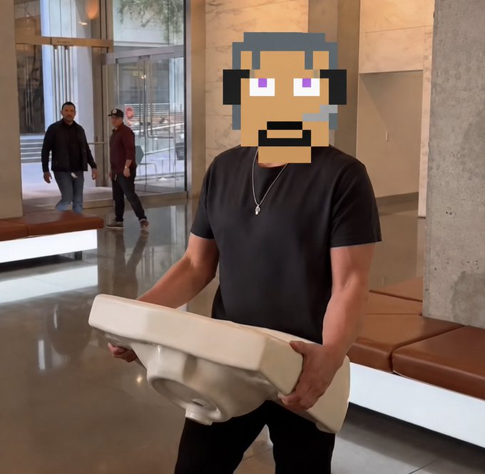 A man in a black t-shirt and silver necklace carrying a white porcelain toilet in what appears to be a hotel lobby, with his face covered by a pixel art emoji.