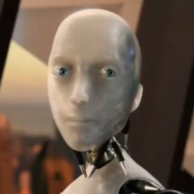 A close-up of a humanoid robot with a smooth white face and expressive blue eyes, appearing to be from a science fiction film.