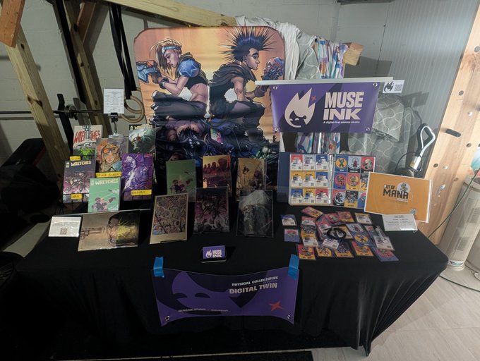A vendor table draped in black cloth showcases art prints, stickers, and other merchandise for 'MUSE INK', featuring a banner labeled 'PERSONAL COLLECTIBLES DIGITAL TWIN'.