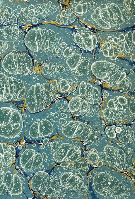 An abstract marbled pattern featuring rounded, pebble-like shapes in teal and green tones, accented with yellow, blue, and black veining throughout.