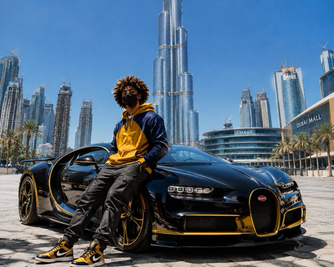 A masked individual with curly hair poses against a black and gold Bugatti Chiron in front of the Burj Khalifa, with "DUBAI MALL" and "EMAAR" signage visible in the background. The image amplifies the caption's message about rising wealth, using Dubai's iconic landmarks and a luxury supercar as symbols of entrepreneurial success.