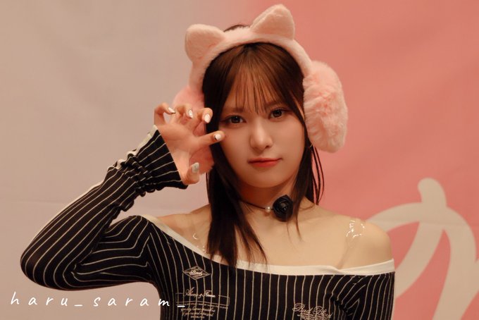 A young woman wearing pink cat ear headphones and a black pinstripe off-shoulder top, posing with her hand up, with watermark text 'haru_saram' visible.