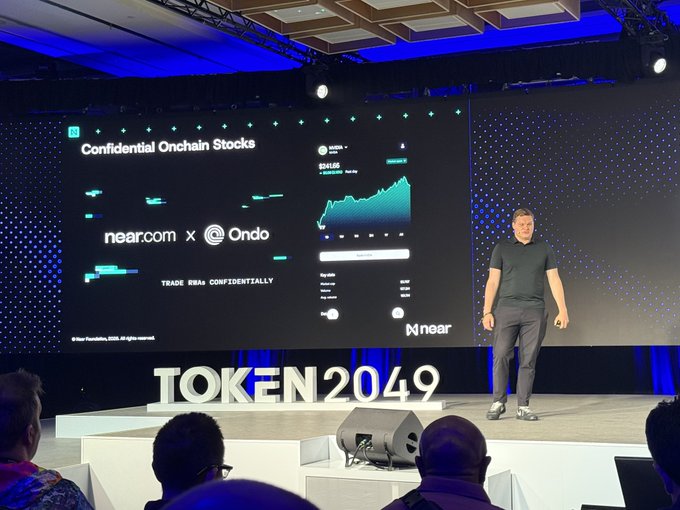 A man presents on stage at TOKEN2049, with a large screen behind him promoting 'Confidential Onchain Stocks' for near.com x Ondo.