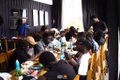 A blurry scene of a group of people seated around a table, appearing to work or study together in an indoor setting.