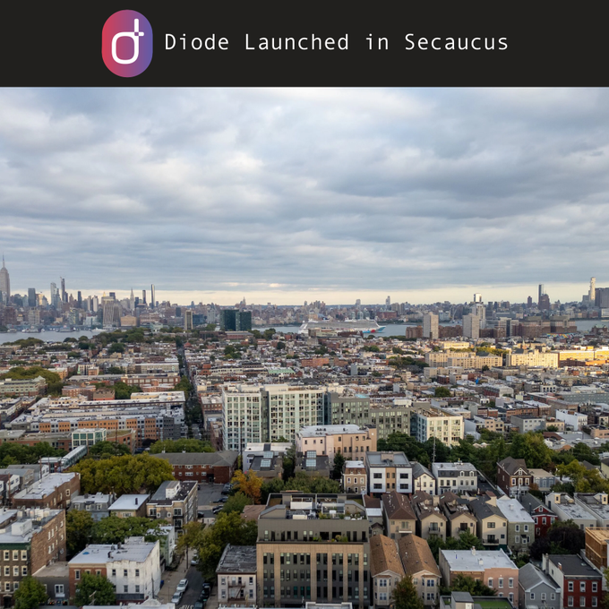 A promotional graphic titled 'Diode Launched in Secaucus' featuring an aerial view of a cityscape with the Manhattan skyline visible in the distance under a cloudy sky.