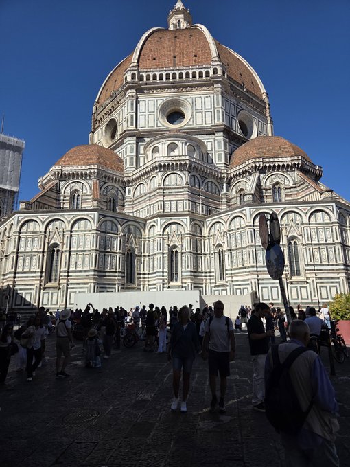 The image shows the magnificent Florence Cathedral (Duomo di Firenze) with its iconic terracotta-tiled dome designed by Brunelleschi, surrounded by tourists in the piazza. This Renaissance marvel in Florence, Italy—the birthplace of modern banking in the 14th century with institutions like the Medici Bank—beautifully illustrates how the city where "banks were invented" also gave the world revolutionary art and architecture.