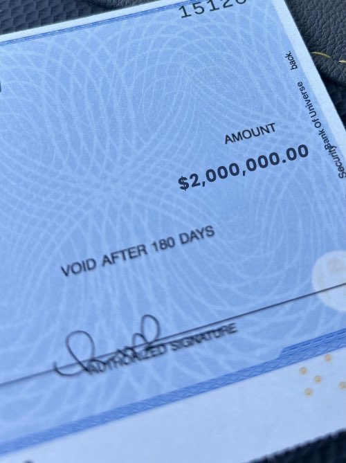 This image shows a large official check made out for the amount of $2,000,000.00, marked "VOID AFTER 180 DAYS," with the text "AUTHORIZED SIGNATURE" visible below a signature line. The image relates to the post as a visual representation of the promised $2 million check being offered to people who comment "222" in connection with $XRP cryptocurrency.