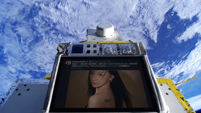 A small screen floating against the backdrop of Earth's clouds displays a tweet announcing EudemoniaCC's new role as Head of Web3 Growth at OKX, showing the partial text "I'M BACK ON THE BATTLEFIELD" alongside her photo.