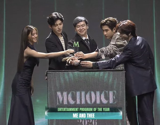 A group of five people on stage celebrate at the "M CHOICE ENTERTAINMENT PROGRAM OF THE YEAR" awards ceremony, with text indicating the winner as "ME AND THEE."
