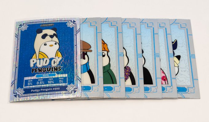 A fanned-out display of Pudgy Penguins trading cards, with the top card featuring a penguin wearing sunglasses and stats including 5% WIN, 0.5% BODY, 10% FACE, and 1% HEAD.