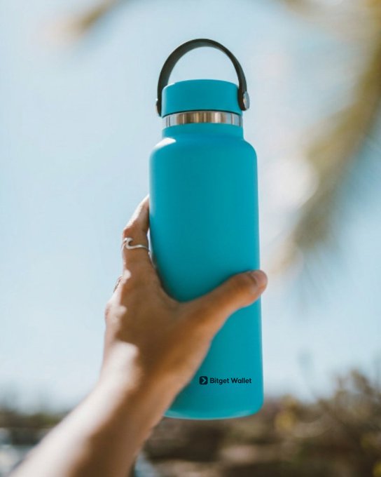A hand holding up a turquoise blue water bottle against a bright sky background, with 'Bitget Wallet' logo visible at the bottom.