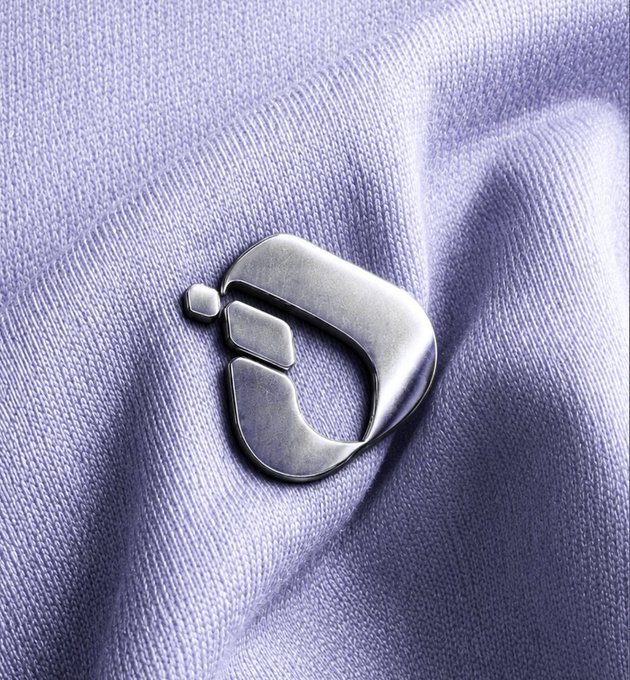 A metallic "D" emblem rests on lavender fabric, visually representing the "D" in "ITL Refunds" being processed and the upcoming InterLink Reverse Auction Buyback.