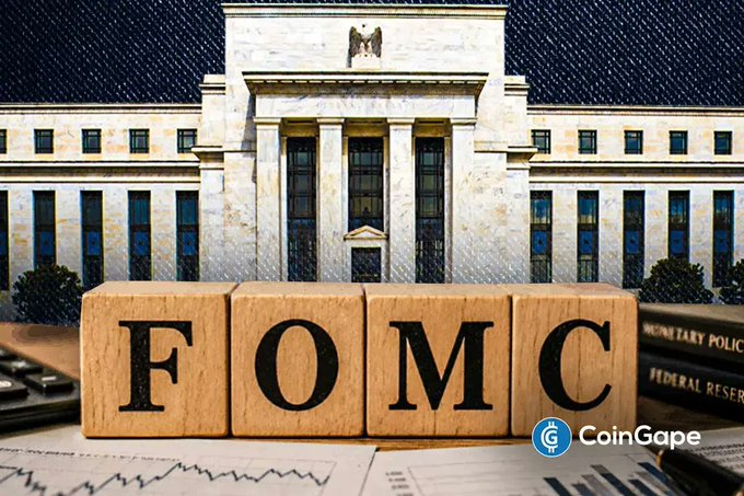 The image shows the Federal Reserve building with wooden blocks spelling "FOMC" in the foreground, along with documents referencing Federal Reserve policy. This visually represents the article's coverage of the Fed holding interest rates steady at the latest FOMC meeting, with the text and imagery emphasizing the central bank's role in the policy decision that impacted Bitcoin's price.