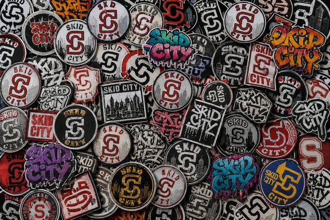 A densely packed pile of various 'SKID CITY' stickers and patches in different colors, shapes, and graffiti-style designs.
