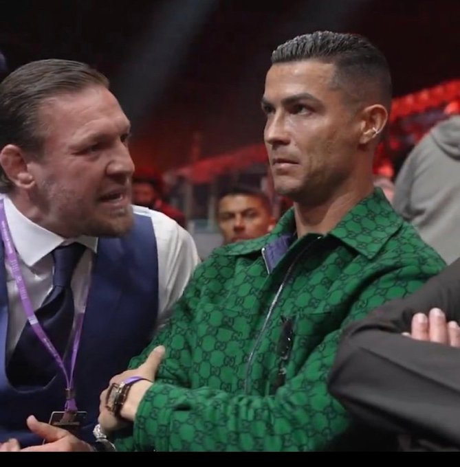 A man in a blue vest and purple lanyard appears to be earnestly pitching something to a stoic Cristiano Ronaldo, who wears a green Gucci monogram jacket and stares ahead with a deadpan expression—capturing the meme's humor about someone trying in vain to convince an unimpressed listener to buy into a dubious chain or scheme.