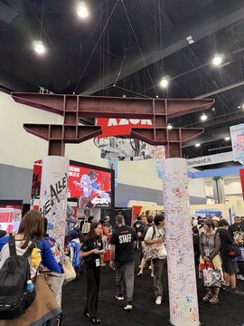Anime Expo attendees gather at the Azuki booth, which features a large wooden torii gate and displays the "AZUKI" and "STAFF" branding as the IP promotes its TCG and upcoming manga to new fans.