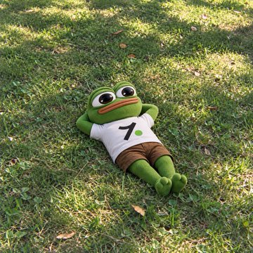 A Pepe the Frog plush toy lying on grass, dressed in a white shirt with the number '7' and brown shorts.