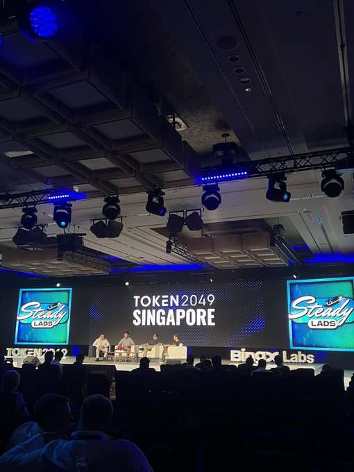 A conference stage at TOKEN2049 SINGAPORE featuring a panel discussion with 'Steady LADS' branding displayed on large screens and 'BingX Labs' signage.