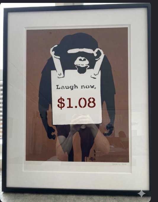 A framed Banksy-style print showing a monkey holding a sign that reads 'Laugh now, $1.08'.