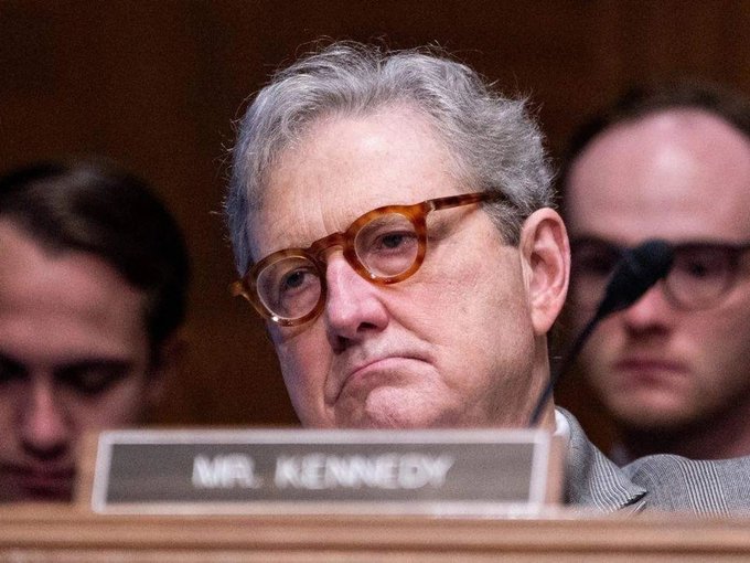 A close-up photo of Senator Mitch McConnell sitting behind a nameplate that reads 'MR. KENNEDY' during what appears to be a Senate hearing.