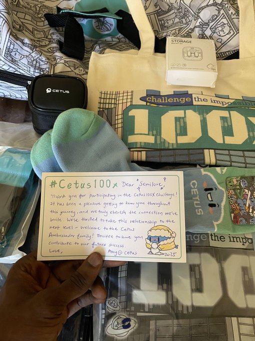 A photo of a hand holding a handwritten thank you note addressed to 'Semilore' from Amy @ Cetus dated 2025, surrounded by Cetus merchandise including socks, stickers, and a storage device.