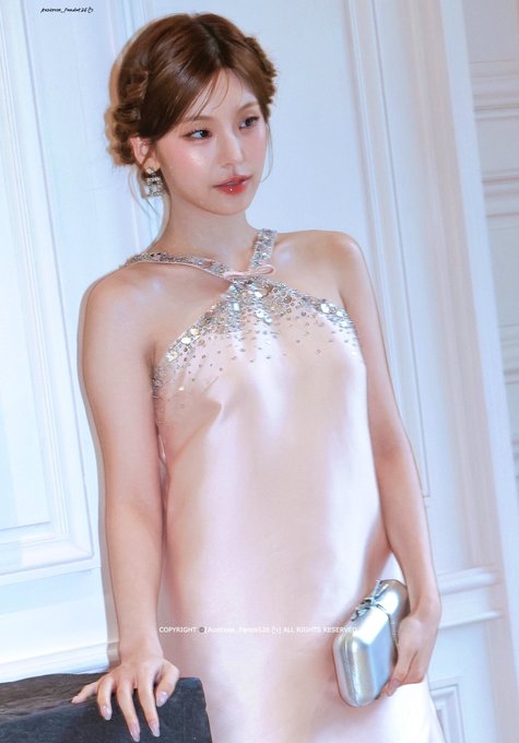 A young woman with auburn hair wears an elegant, pale pink satin halter dress adorned with crystals, holding a silver clutch; a copyright watermark from 'jinsoul_foodie' is visible.