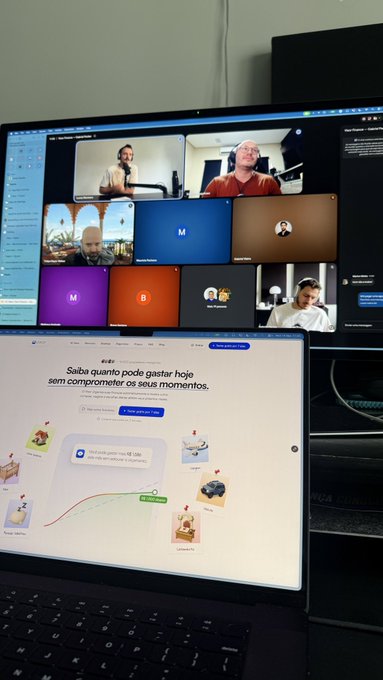 A laptop screen displays a Google Meet video conference with multiple participants and a Google Discover page showing Portuguese text 'Saiba quanto pode gastar hoje sem comprometer os seus momentos.'