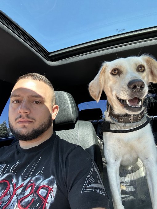 iced car with a man and dog, both smiling, on the driver's seat and passenger seat respectively.