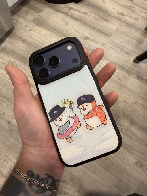 A hand holding a smartphone with a black-bordered case featuring an illustration of two snowmen wearing hats and scarves in a snowy scene.