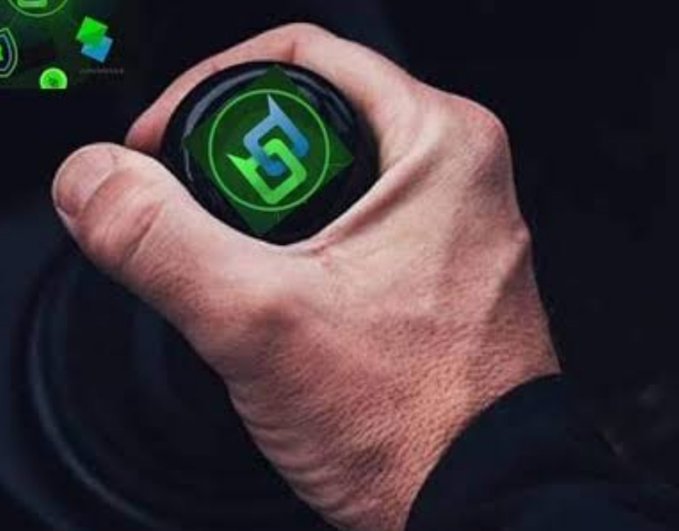 A close-up of a hand gripping a gear shift knob displaying an illuminated green logo.