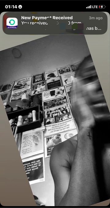 A black-and-white photo of newspaper clippings and papers spread on the floor, with a payment notification visible at the top of the screen.