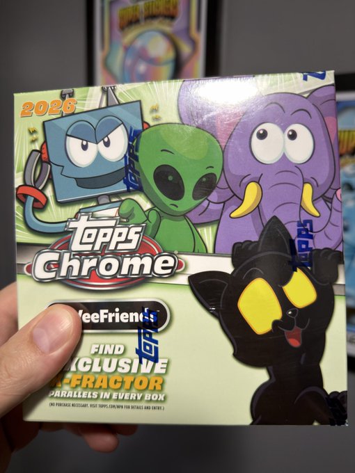 Hand holding a 2026 Topps Chrome 'WeeFriends' trading card box featuring cartoon characters including a blue robot, green alien, purple elephant, and black cat.