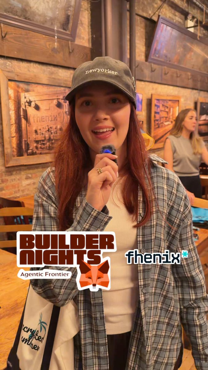 The image features a woman wearing a plaid shirt with a baseball cap on her head. She has a smile on her face as she poses for the camera. The background of the photo shows a brick wall, which adds an interesting element to the scene. There is also a text overlay in the image that reads "made people yap about privacy in exchange for @fhenix swag at @MetaMask Builder Night today if this doesn't make you FOMO, you should probably log off and never open this app again". The woman's smile suggests she is enjoying herself despite the presence of the text.